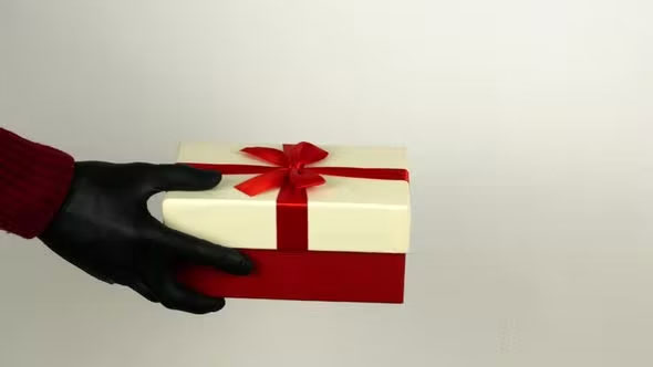 A man gives a woman a gift box in black COVID 19 gloves